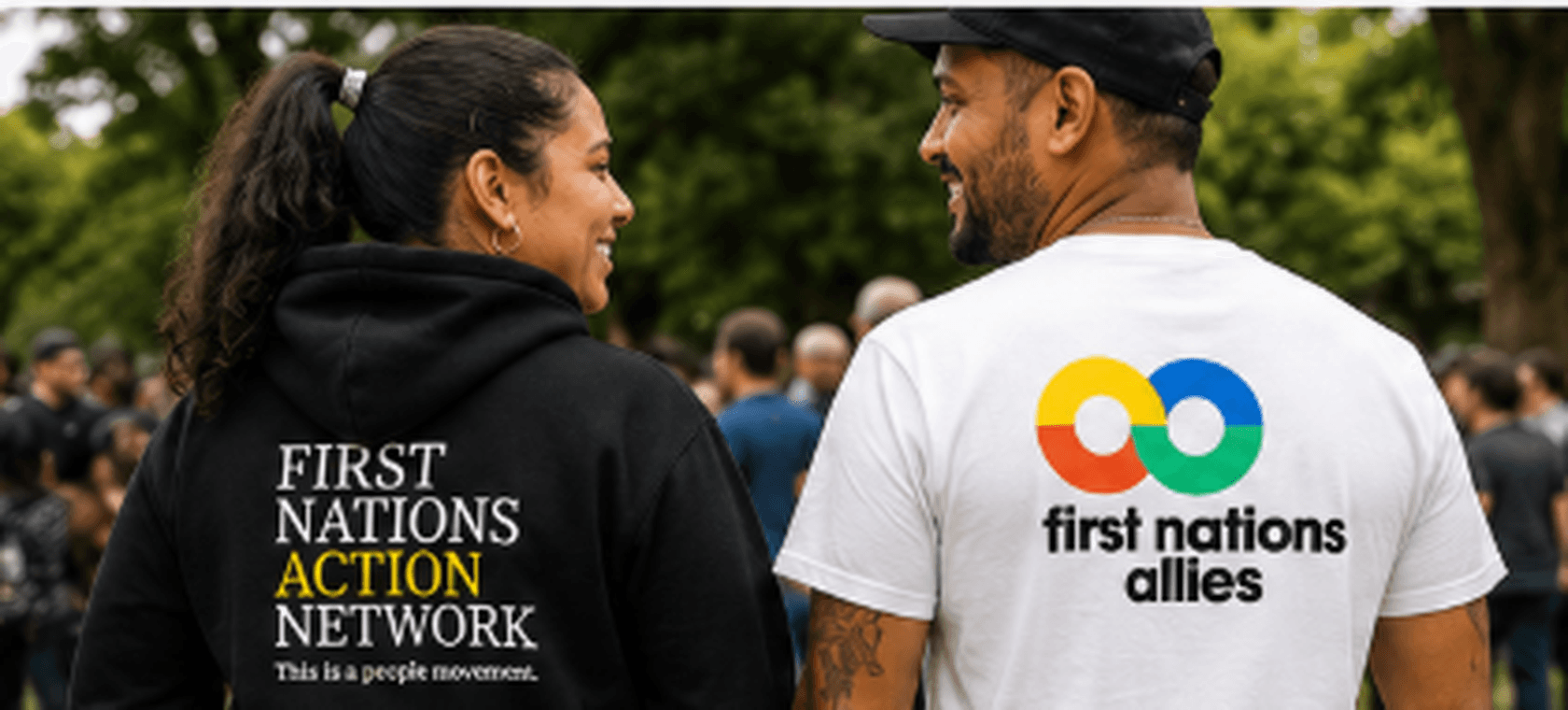 Two people seen from behind wearing First Nations Action Network and First Nations Allies merchandise at a community gathering